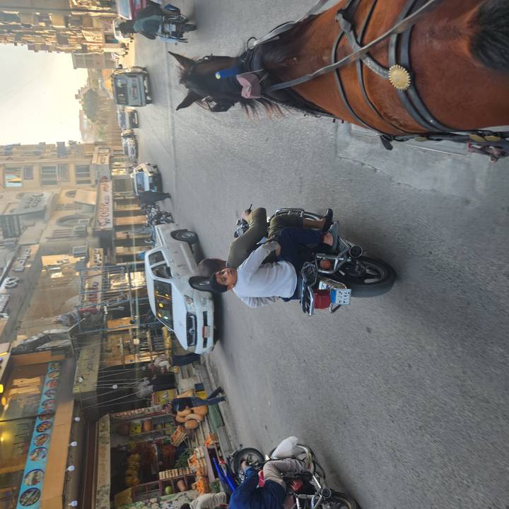 Two boys ride pillion on a motorbike through a busy Egyptian city street.