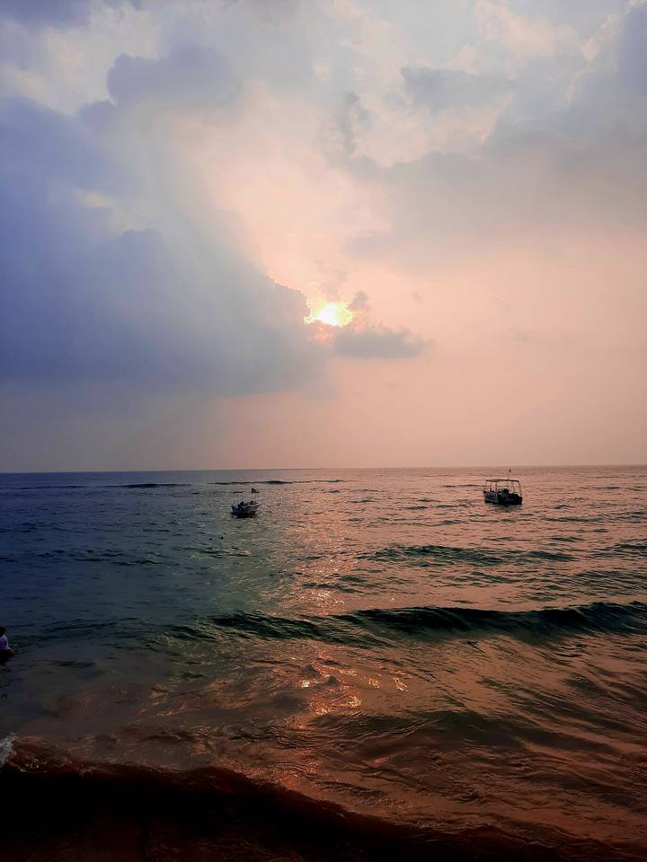 Soft pastel sunset over the Indian Ocean with two small fishing boats floating on gentle waves