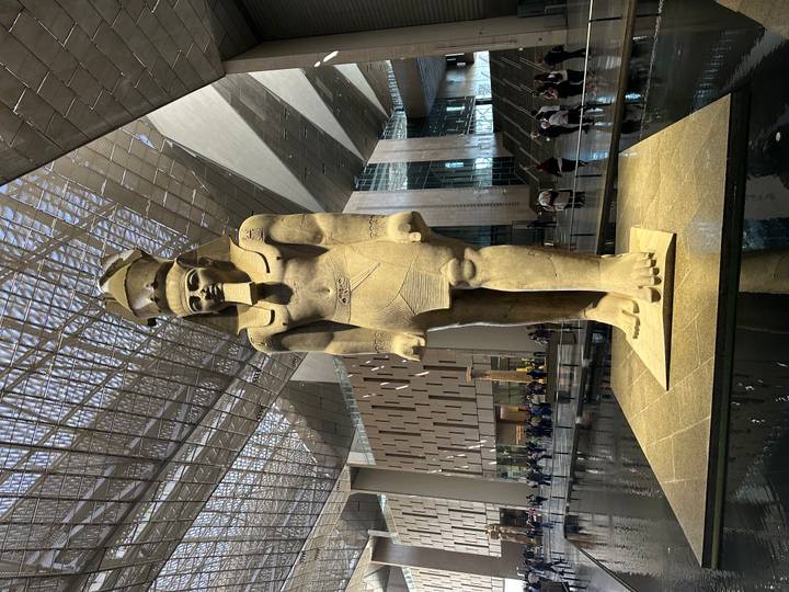 Giant statue of a pharaoh standing in the airy atrium of the Grand Egyptian Museum