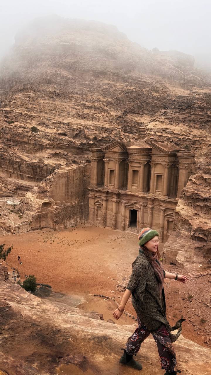 Impressive view of Petra’s Monastery carved into rose-red cliffs as a lone traveler gazes from the overlook.