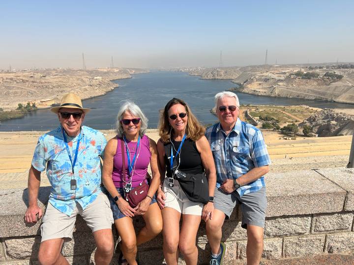 Four travellers pose on a terrace overlooking the Nile and desert at Aswan High Dam