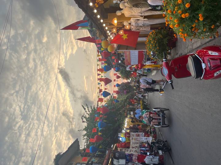 Lantern-lined street market in Hội An bustling with visitors beneath evening sky and flags