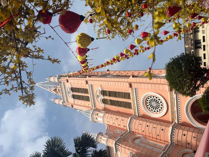 Ornate pink Tan Dinh Church adorned with festive lanterns against a bright sky in Ho Chi Minh City