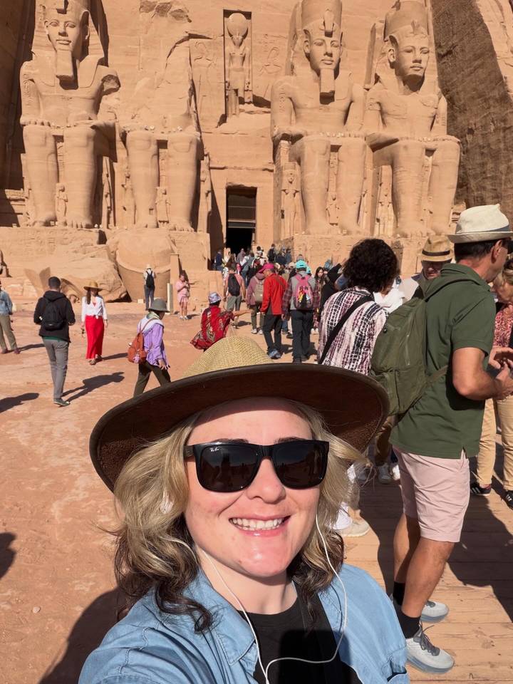 Traveler’s selfie with crowds outside colossal seated statues carved in Abu Simbel temple façade.