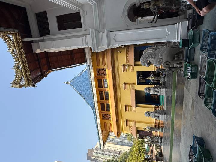 Colorful temple complex with stone lion statues and golden roof details under a clear blue sky.
