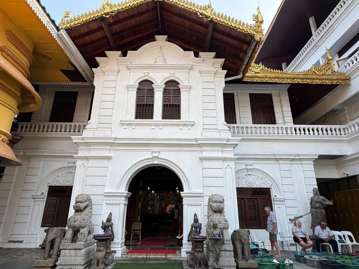 White colonial-style building with arched entry flanked by stone guardian statues.
