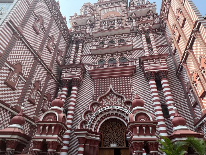 Red-and-white striped facade of the ornate Jami Ul-Alfar Mosque viewed from street level.
