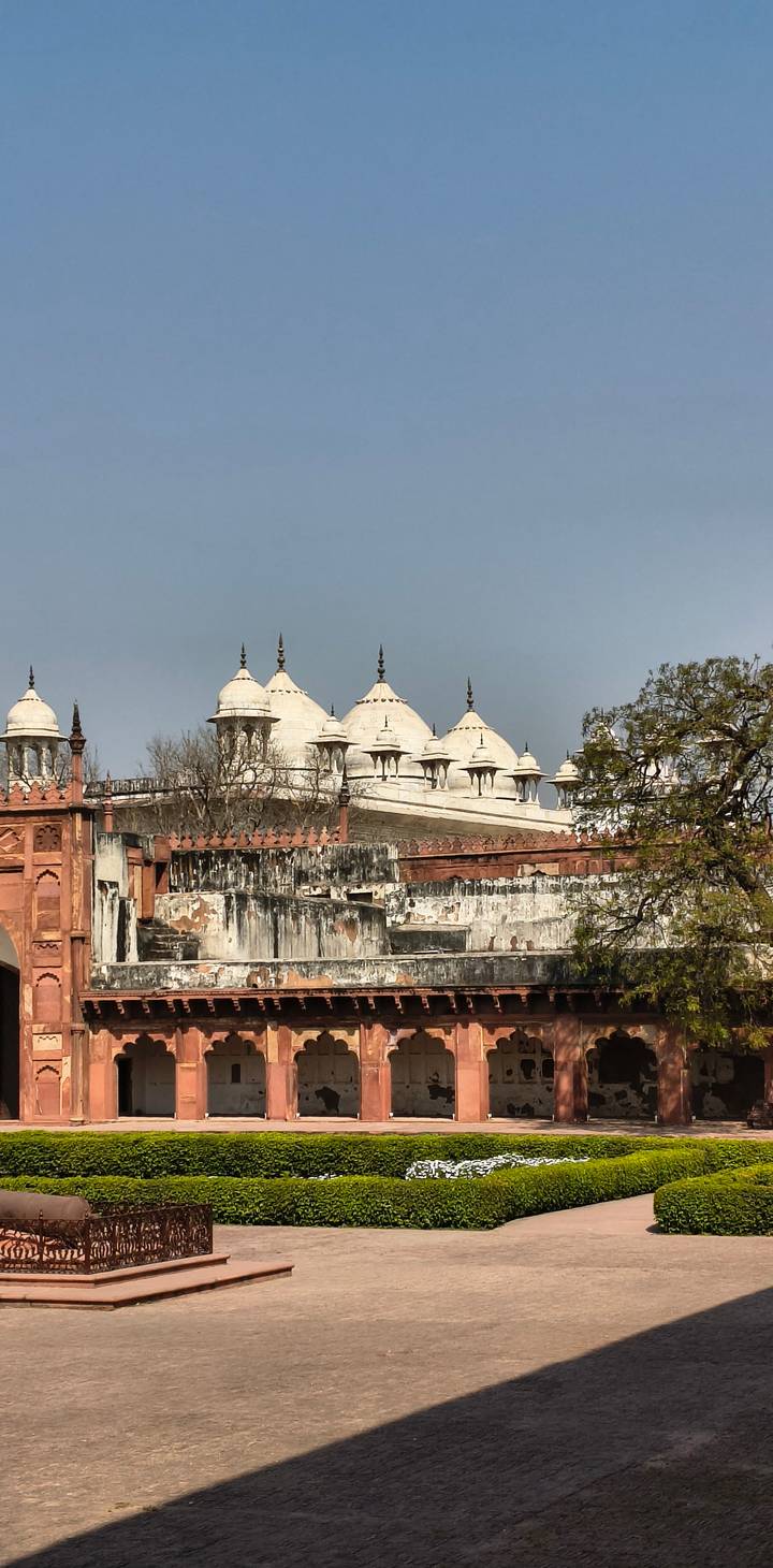 Detail of weathered red sandstone walls and white marble pavilions of a Mughal fort.