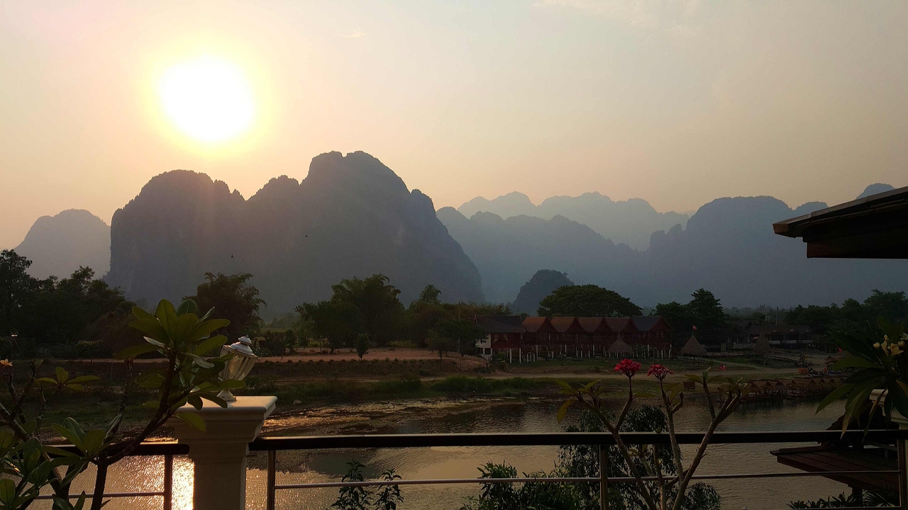 A serene landscape with a river, mountains, and sunset.