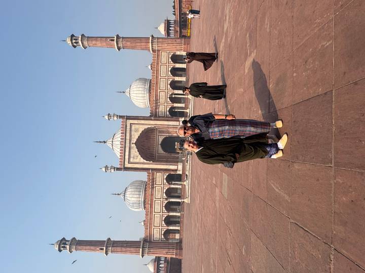 Couple poses in the vast courtyard of Jama Masjid with its domed gates in the background.