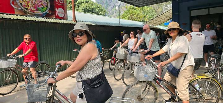 Tour group on bicycles preparing to ride along a shaded lane in rural Vietnam.