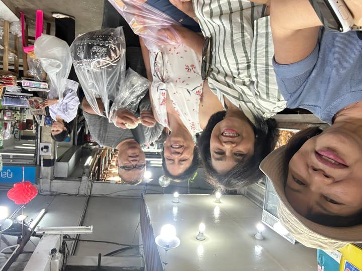 Travellers shopping for snacks at a bustling indoor market stall.