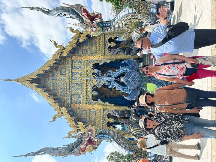 Friends standing in front of the ornate blue and gold façade of Chiang Rai’s Blue Temple.