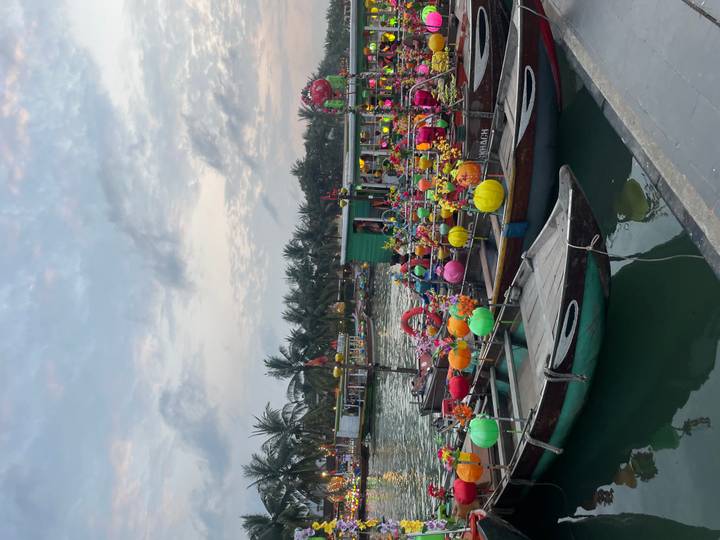 Hoi An river scene with brightly painted lantern boats at dusk under a pastel sky.