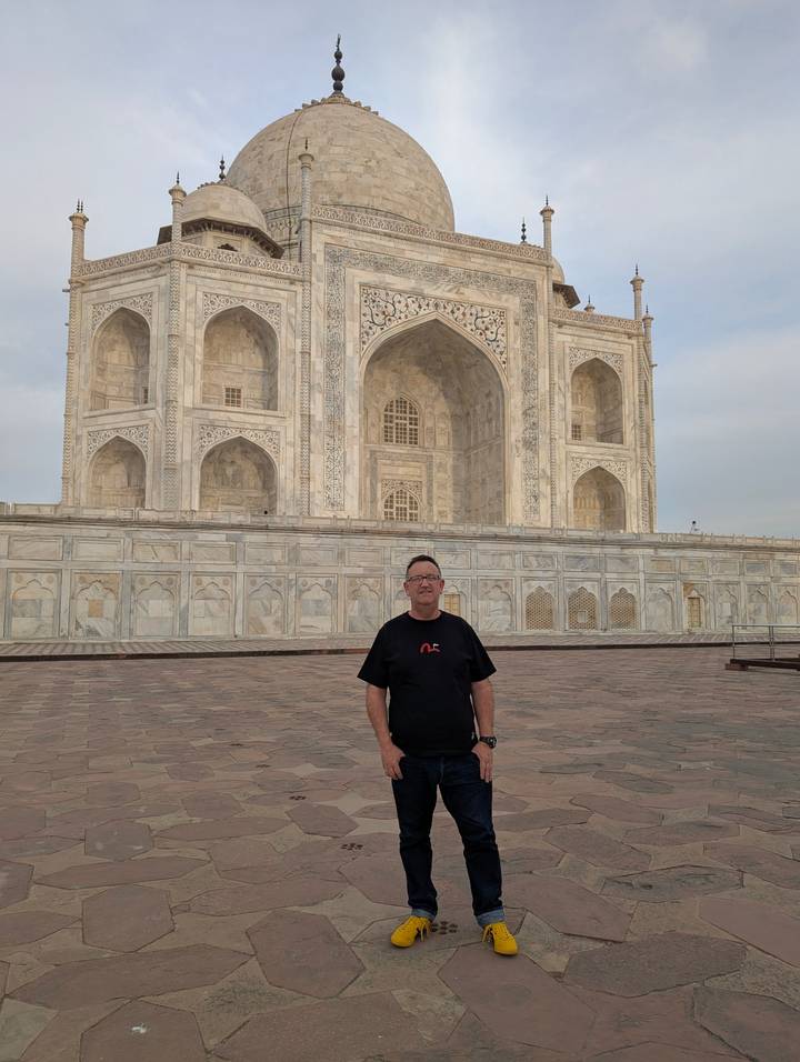 Visitor poses in front of the ornate marble façade of the Taj Mahal in Agra.