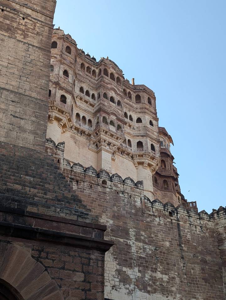Stone bastions and intricate balconies of Mehrangarh Fort rise dramatically into a clear sky.