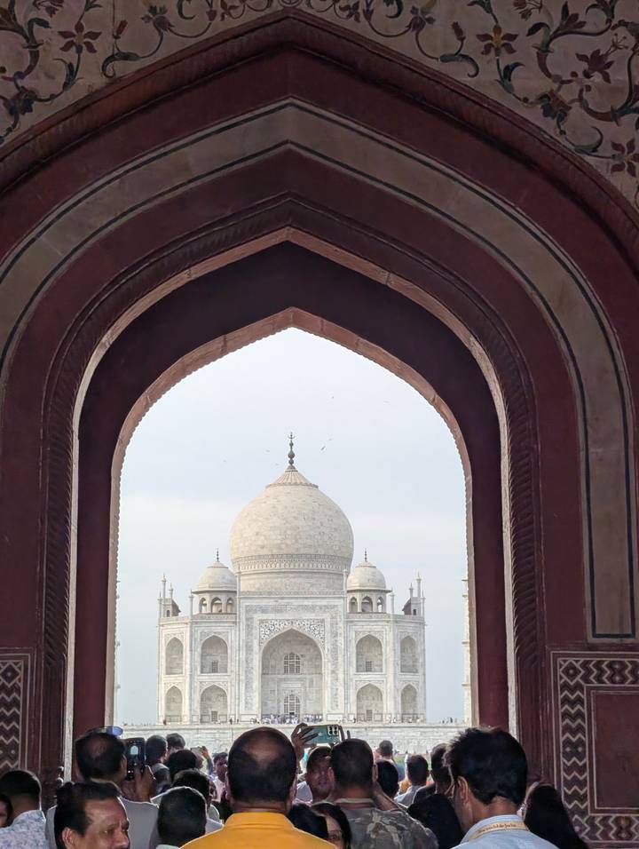The white dome of the Taj Mahal framed perfectly within a dark Mughal archway.