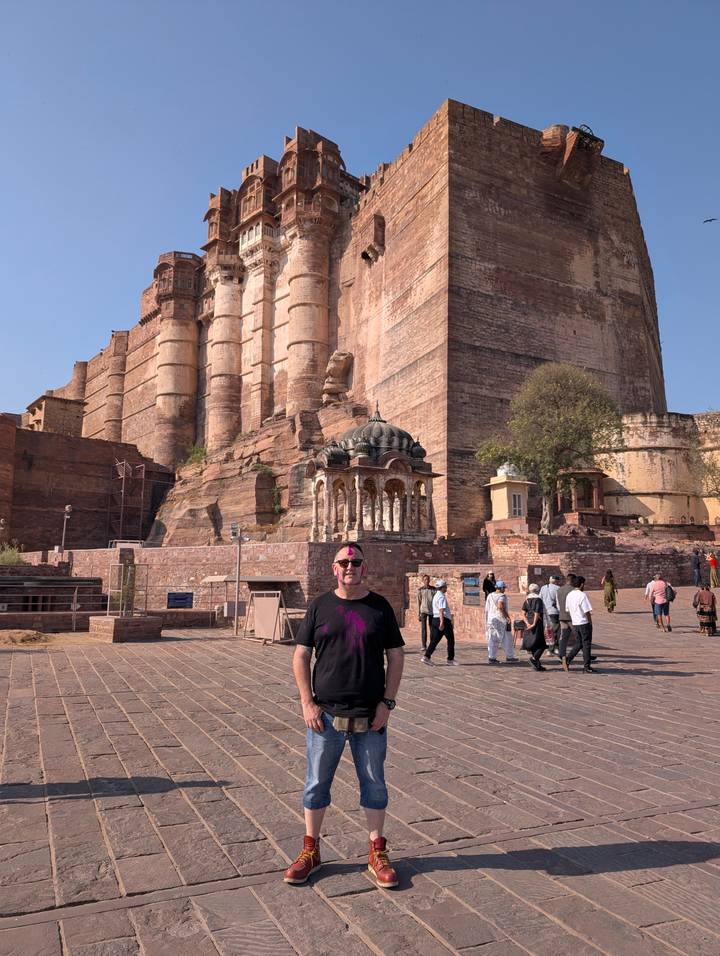 Visitor with Holi powder stands before the towering stone walls of Mehrangarh Fort in Jodhpur.