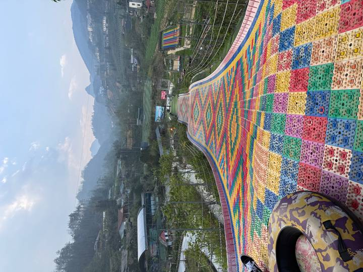 Long multicolored plastic slide winding downhill in a mountain amusement park near Sapa.