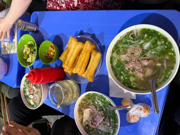 Duplicate pho and street-food spread on blue table.