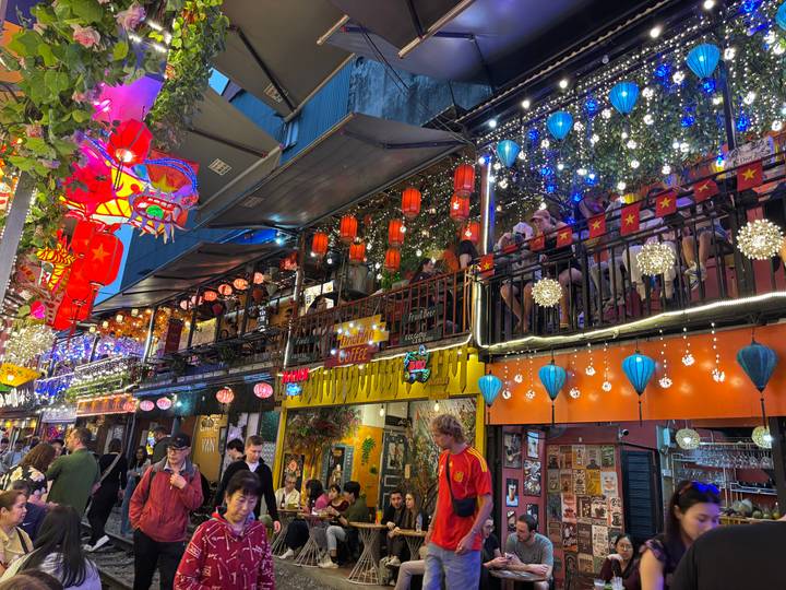 Vibrant multi-level bar street illuminated with lanterns, fairy lights and crowds enjoying nightlife.