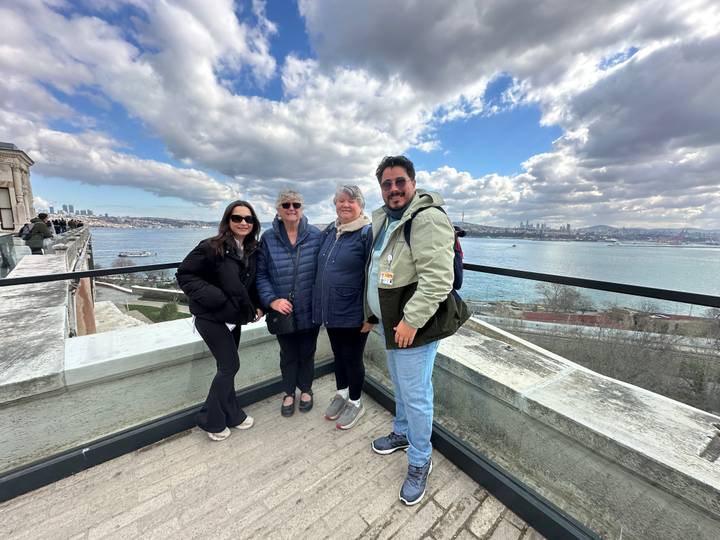 Group of travellers pose on a terrace overlooking the Bosphorus and Istanbul skyline.