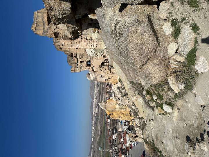 Rock-hewn cliffs and cave dwellings of Cappadocia under a clear blue sky.