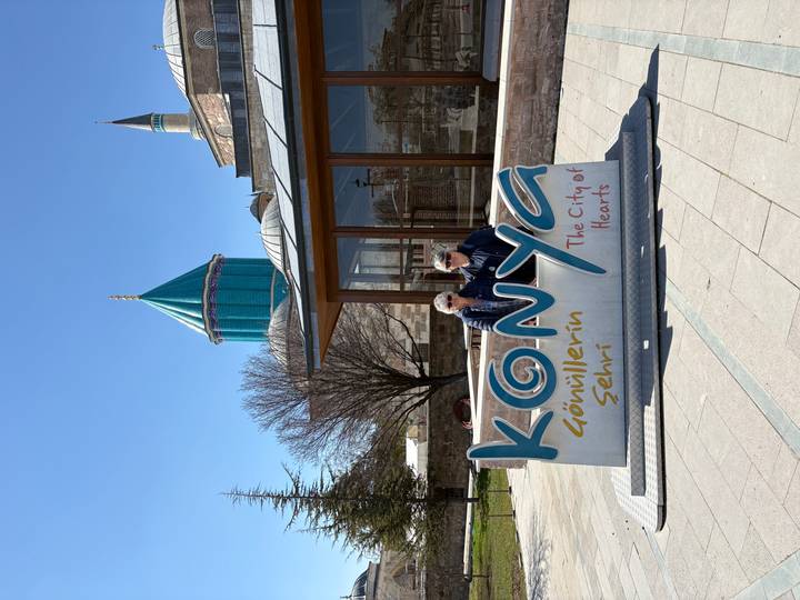 Visitors pose by the colourful KONYA city sign near the Mevlana Museum’s turquoise dome.