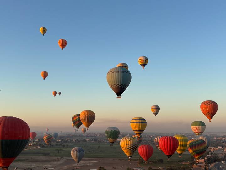Dozens of hot-air balloons float above the Nile valley at dawn.