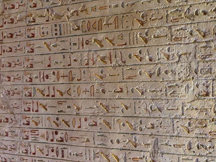 Close-up of colourful hieroglyph inscriptions carved into an ancient temple wall.