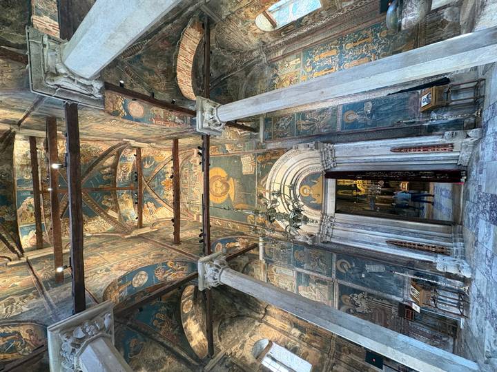 Richly frescoed interior of a historic monastery with marble columns and arched doorway.