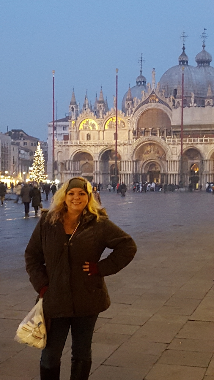 A person posing in front of St. Mark's Basilica during Christmas.