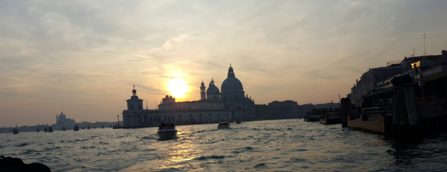 Sunset view of Venice with silhouettes of buildings.