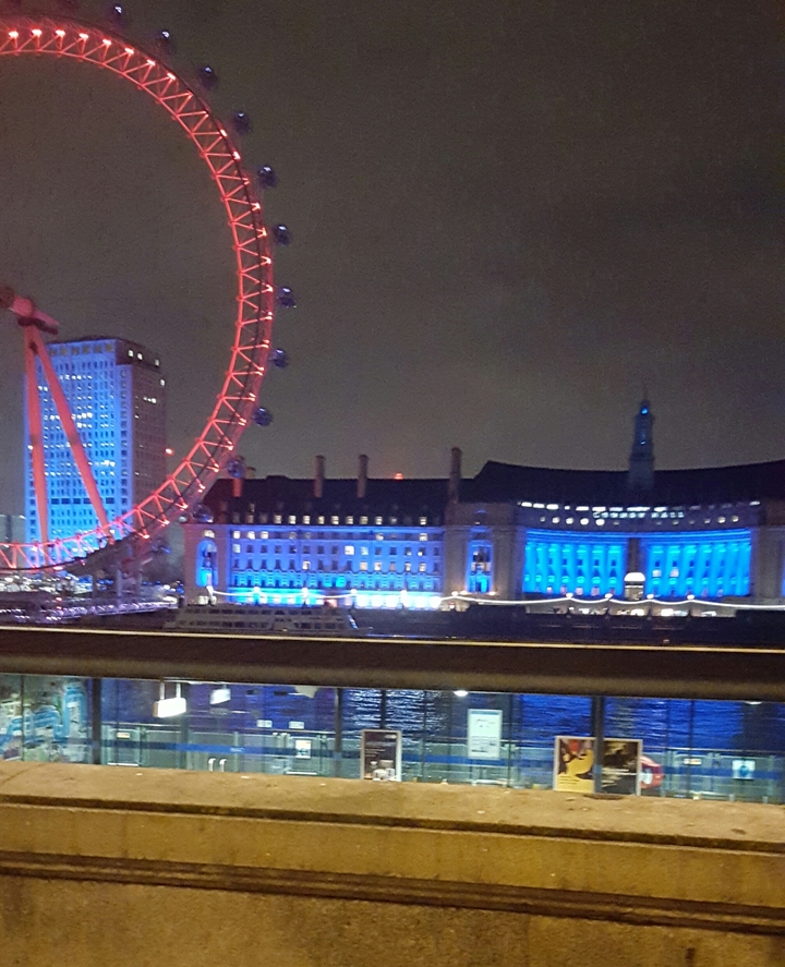 Night view of the London Eye and lit-up building.
