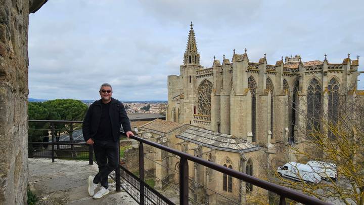Man standing by a railing with the gothic basilica of Carcassonne rising behind him.