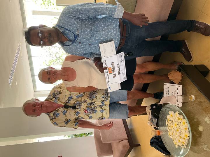 Two tourists meeting their Sri Lankan guide in a hotel lobby, holding a welcome sign.