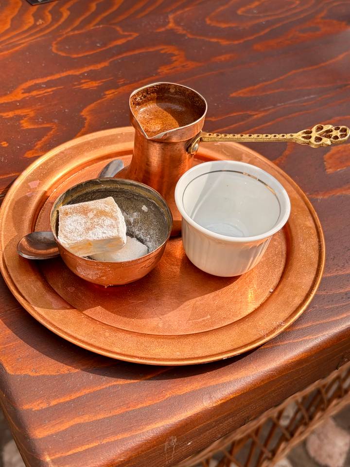 Traditional copper tray with a cezve, powdered Turkish delight cube and empty ceramic cup.