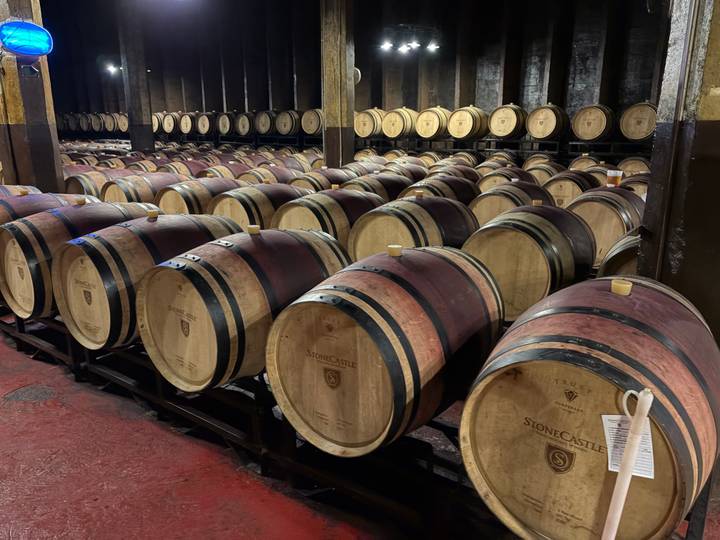 Rows of oak wine barrels aging in a dim cellar with StoneCastle branding.
