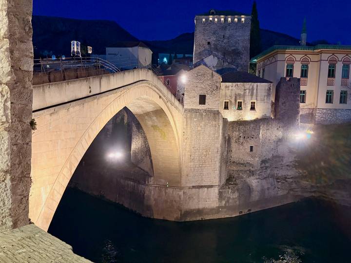 Evening view of the illuminated Stari Most bridge arching over the emerald river in Mostar.