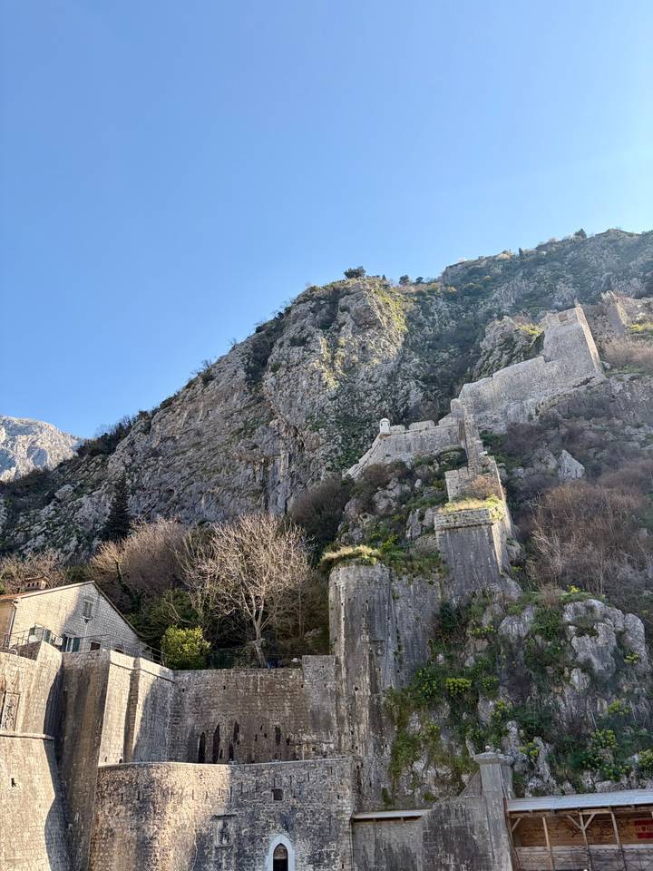Steep limestone cliffs with ancient fortress walls climbing the mountainside above Kotor.
