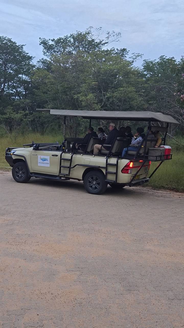 Open-air safari vehicle carrying tourists along a park road