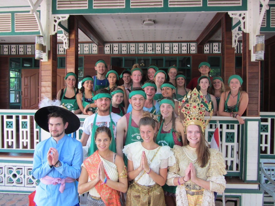 A large group of people dressed in costumes posing in front of a traditional building.
