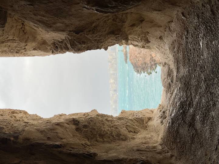 View of a windy seascape through a rough stone window opening in an ancient wall.
