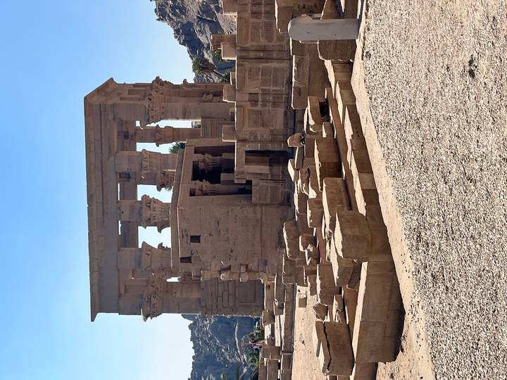 Stone ruins and columns of the Temple of Philae under a bright blue Egyptian sky.