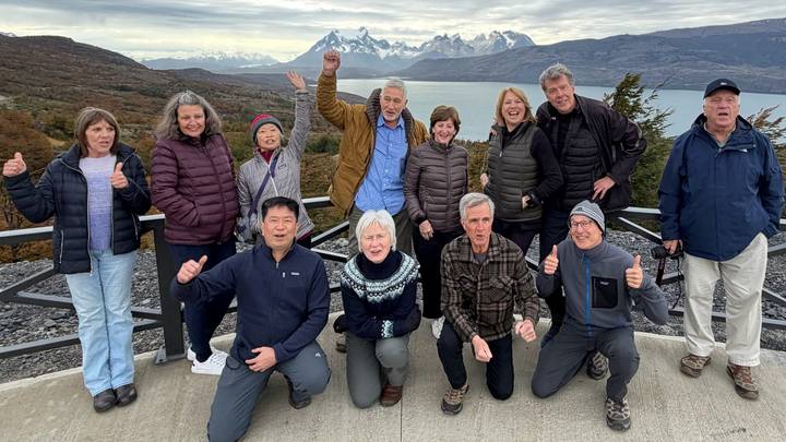 Happy tour group posing on terrace overlooking Torres del Paine peaks and lake
