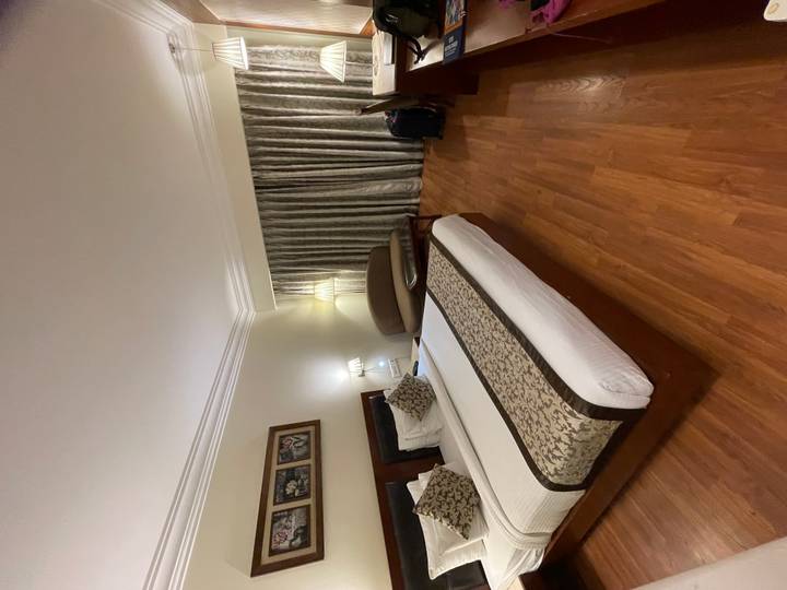 Well-appointed hotel room featuring a king bed, wood flooring, patterned runner and neutral décor.