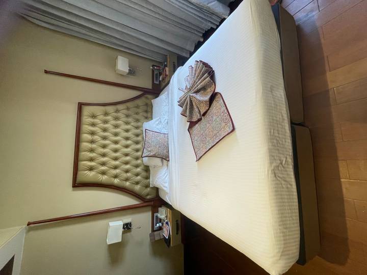 Neatly made hotel bed with decorative patterned linens arranged atop crisp white sheets.