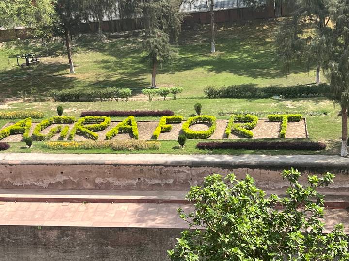 Topiary letters spelling 'AGRA FORT' within green lawns viewed from above.