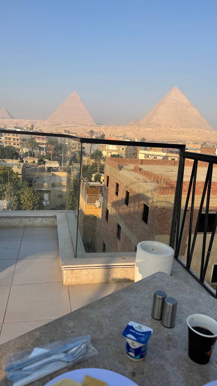 Urban balcony with glass railing overlooking unfinished brick buildings and desert hills beyond