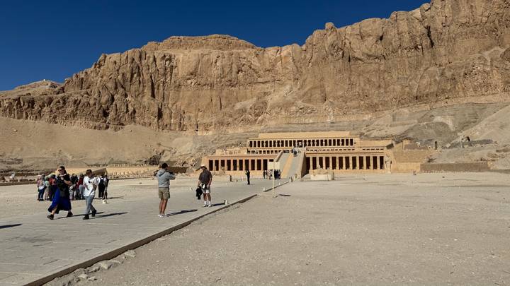 Wide courtyard facing the terraced limestone Temple of Hatshepsut set against towering cliffs